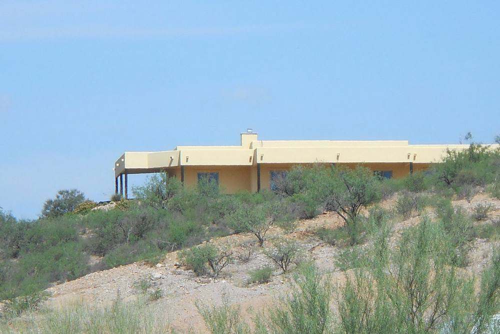 A low flat-roofed desert house on a hillside under a blue sky