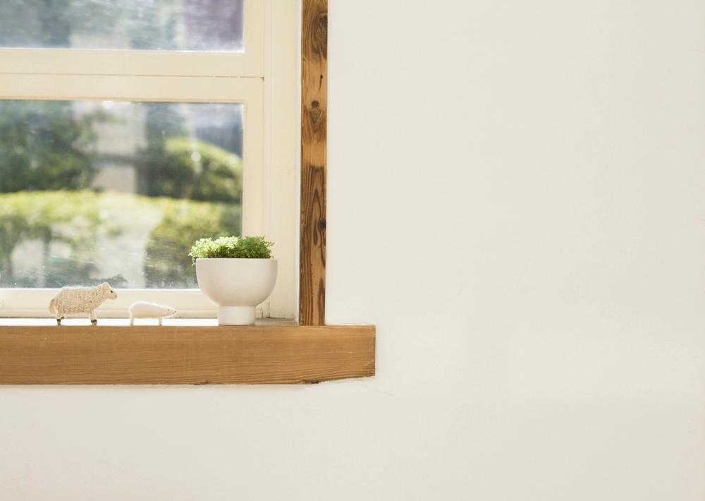 A quiet painted interior corner with a wood window sill